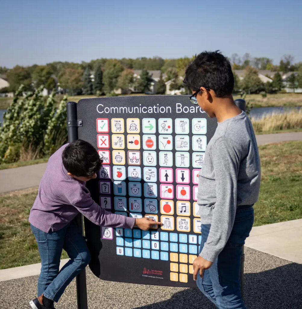 2 kids pointing at symbols on communication board.