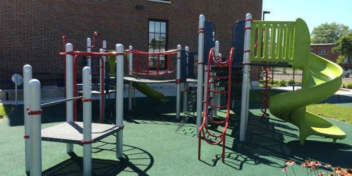 Photo of a play structure with climbers, multiple decks, and a slide