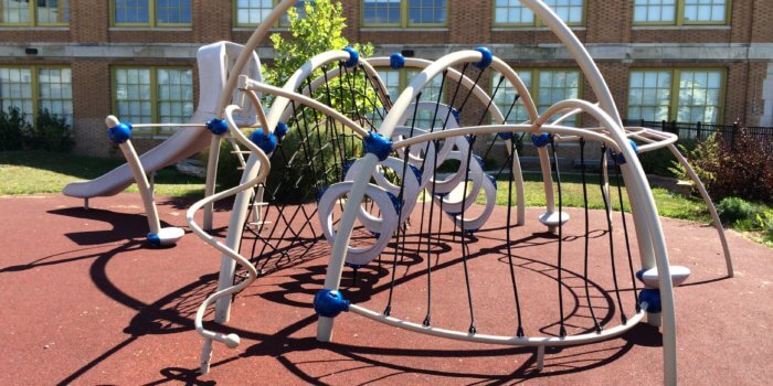 Photo of arching play structure with nets, climbers, and a slide
