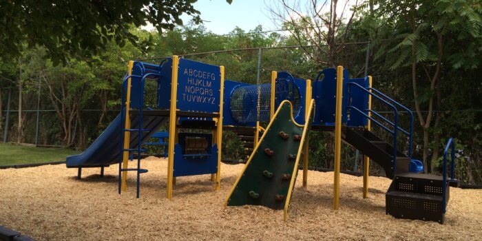 Photo of a playground with several decks, climbers, and slide