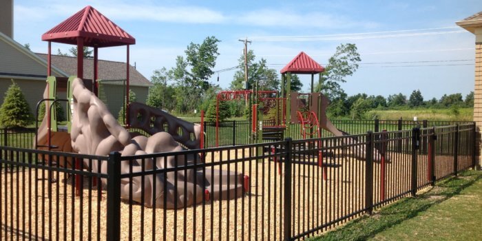 Photo of play structures with slides and climbers, enclosed by a fence