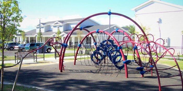 Photo of an arching play structure, featuring several different climbers and components