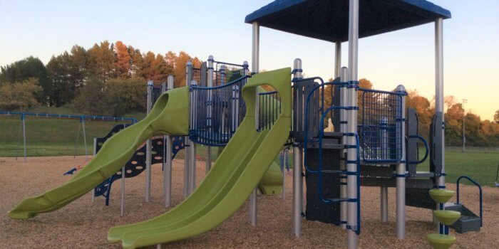 Photo of a play structure with roof, multiple decks, slides, and climbers