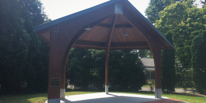 Photo of an open outdoor wood shelter with a peaked roof and arched openings