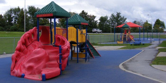 Photo of play structures with decks, roofs, slides, and climbers, as well as shade structures