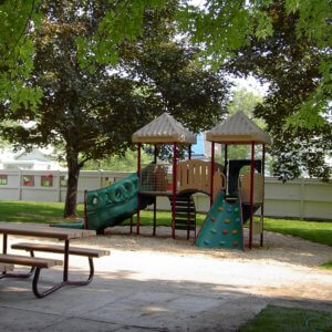 Photo of playground with slides and climbers, and picnic tables.