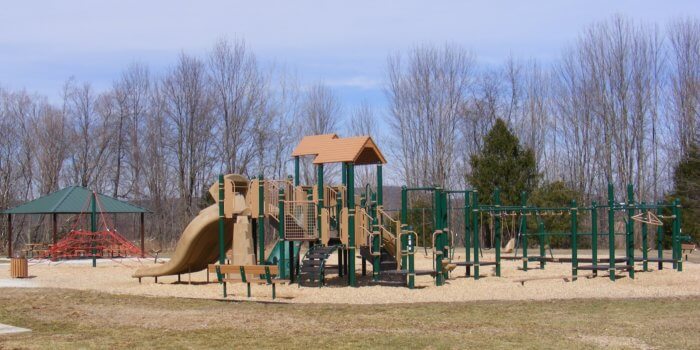 Photo of playground with slides, climbers, overhead components, and a net climbing structure.