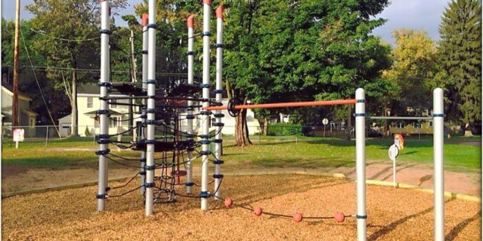 Photo of playground with net climbing structure and attached play components.