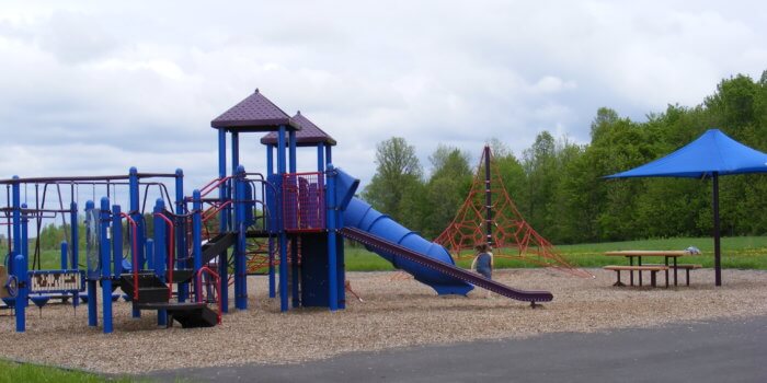 Photo of playground with slides, climbers, and rope climbing structure.