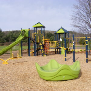 Photo of large play structures with slides, nets, and climbers, and a large spinner in front