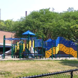 Photo of a large play structure with climbing walls, slides, and overhead climbers