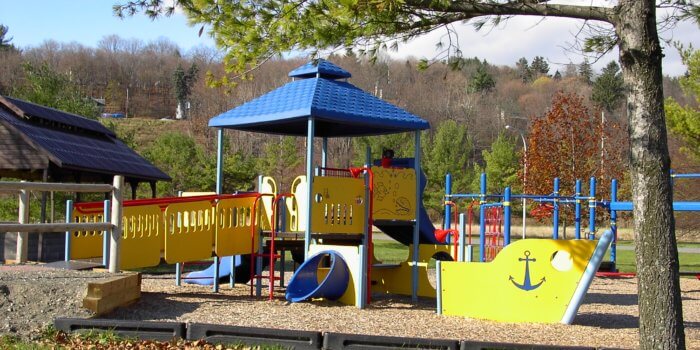 Photo of playground with boat-shaped play structure and marine themed play panels.