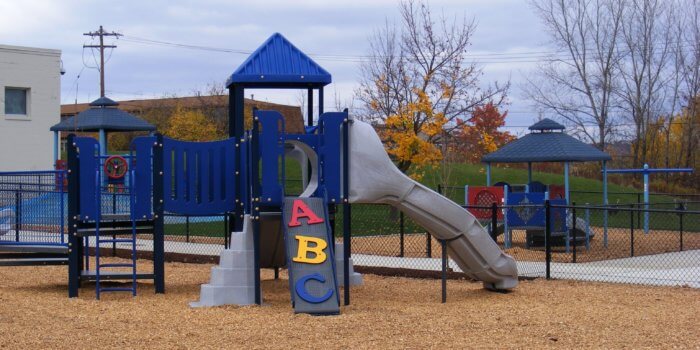 Photo of playground with several play structures, with play panels, slides, and climbers.