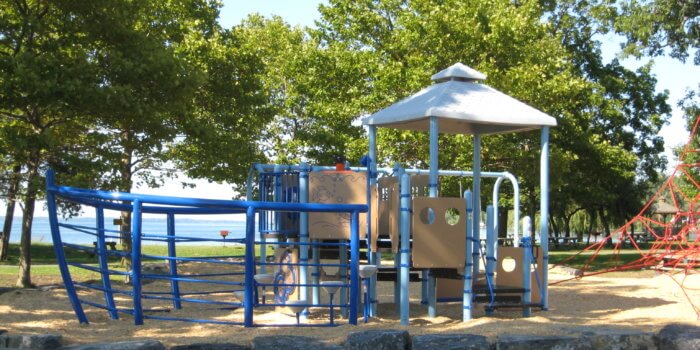 Photo of a ship-inspired play structure, with decks, climbers, and play panels