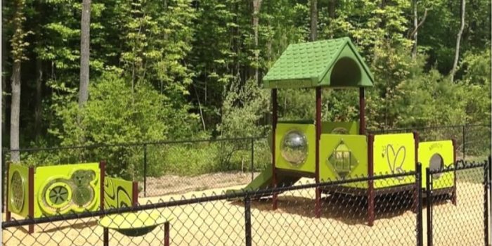 Photo of playground with climbers, slide, and play panels.