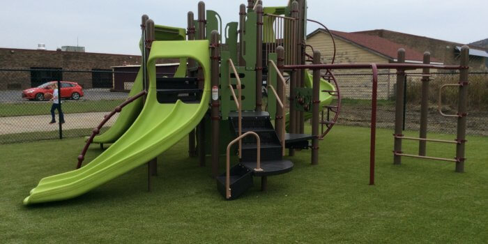 Photo of a play structure with multiple decks, slides, and climbing components.