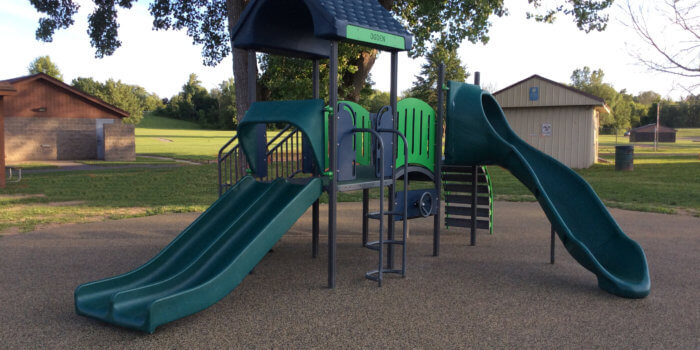 Photo of play structure with slides, climbers, and a bridge.