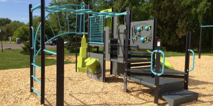 Photo of play structure with climbers, a slide, and play panels.