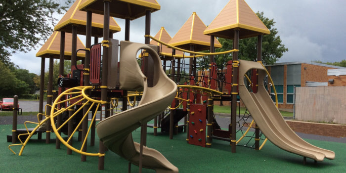 Photo of playground with slides, climbers, pointed roofs, and bridges.