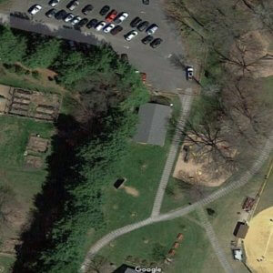 Aerial photo of the park prior to playground installation, with a baseball field, parking lot, and grassy area