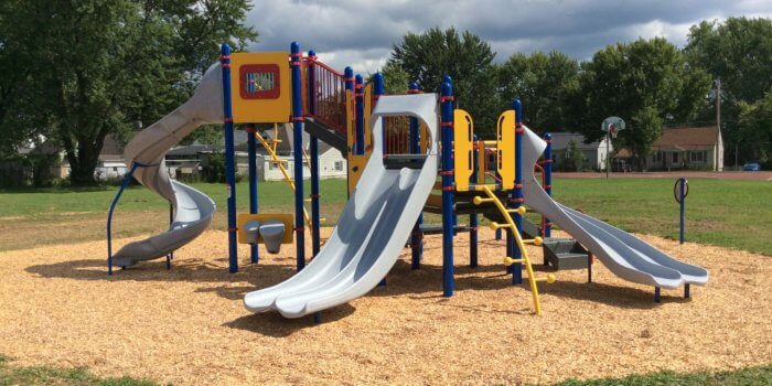 Photo of a playground structure with multiple slides, climbers, and panels.