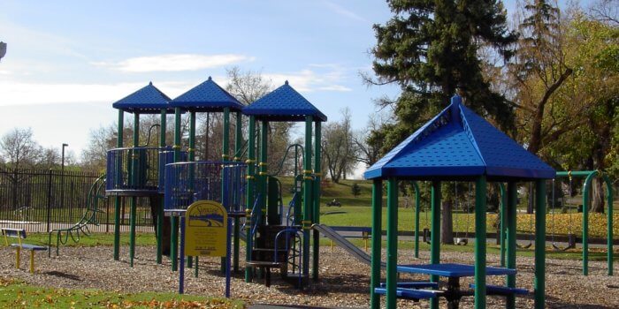 Photo of playground with swings, slides, climbers, and a covered picnic table.