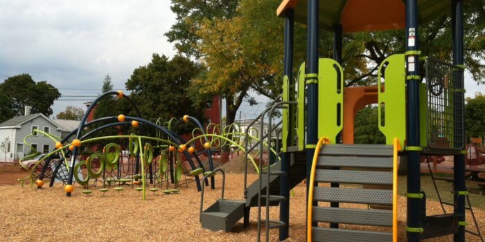 Photo of play ground with slide, climbers, and curved climbing structure.
