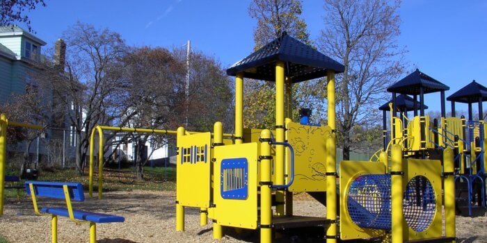 Photo of playground with swings, climbers, tunnels, slides, and play panels.