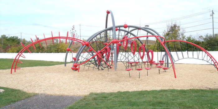 Photo of curved climbing structure with nets, steppers, and bars.
