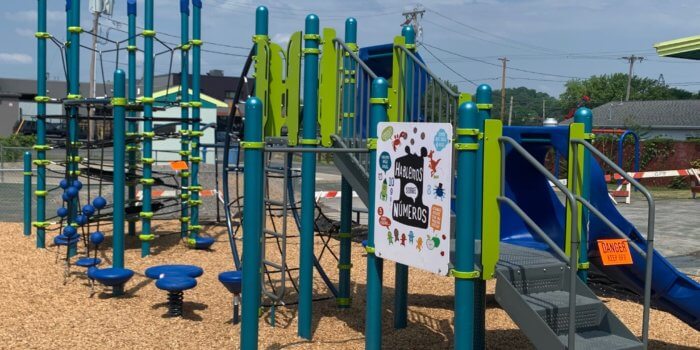 Photo of playground with slides, climbers, play panels, and climbing net tower.