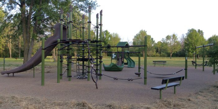 Photo of a multi-post netted play structure with a slide and other play components.